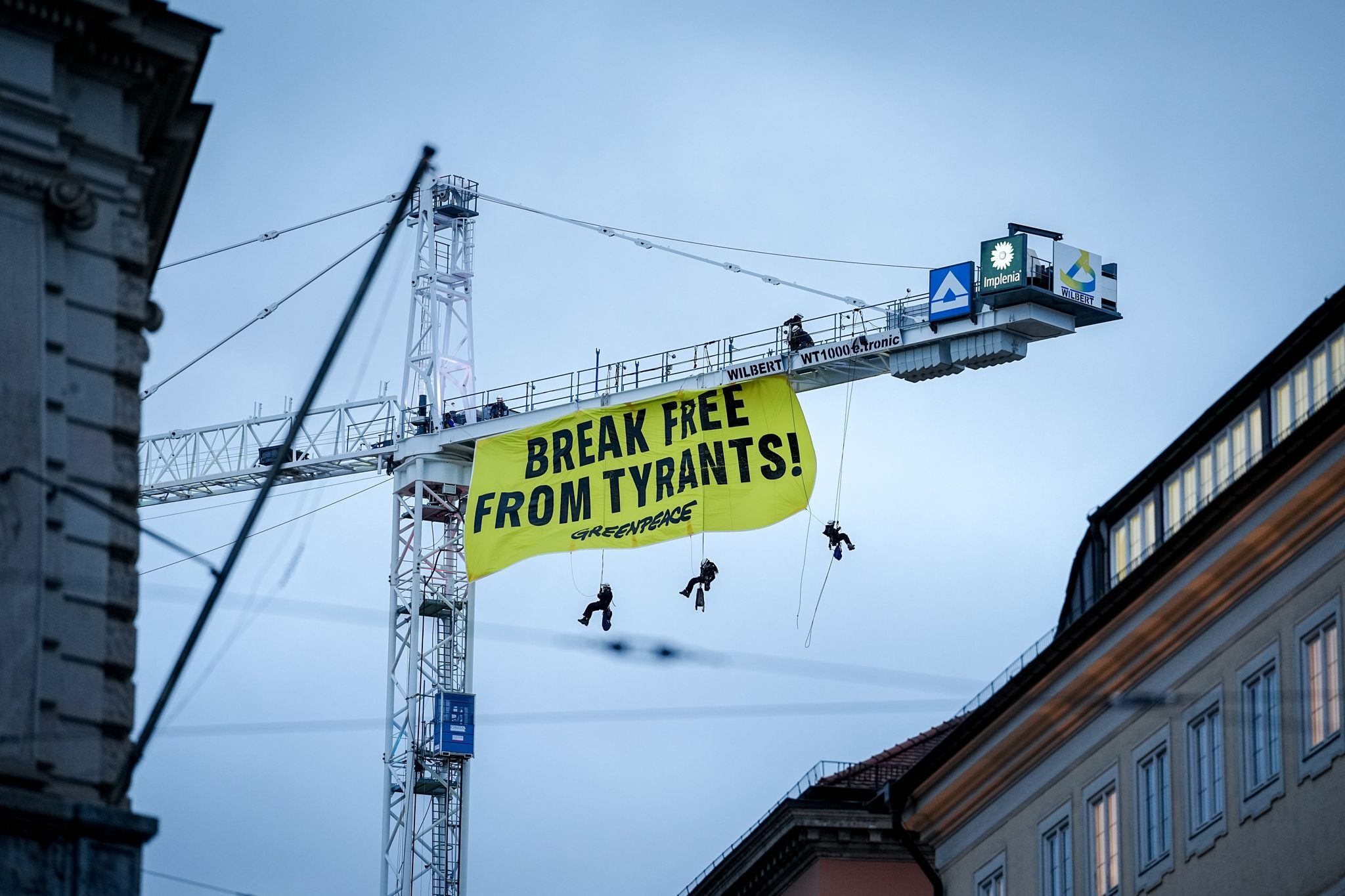 Kletterer entrollen Protest-Transparent an Kran in München